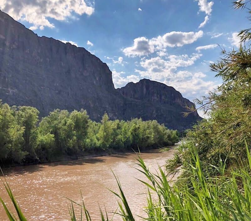 Muddy river with mountains in the background.